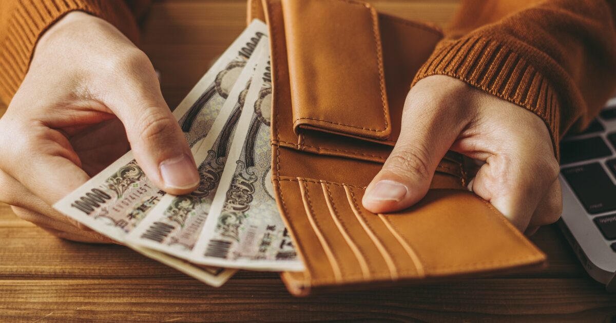 茶色の財布から日本円の紙幣を取り出す手元の節約イメージ