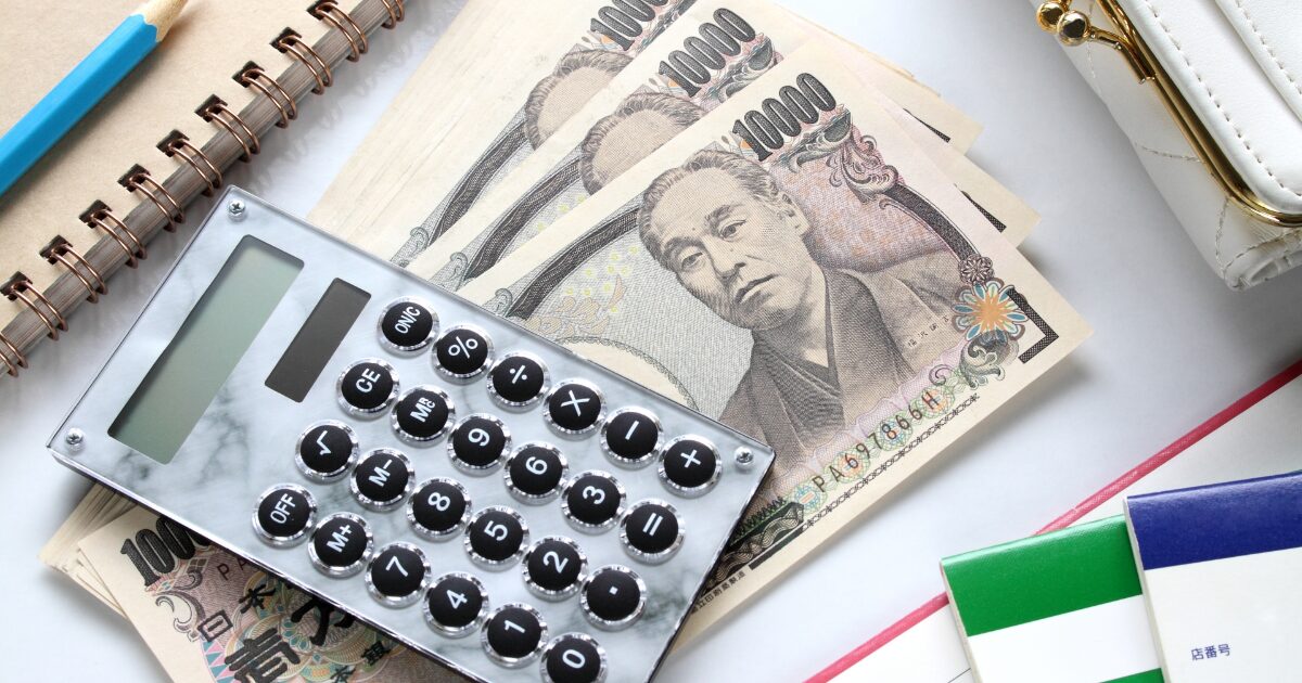 電卓とノートと日本円紙幣で家計管理をするイメージ