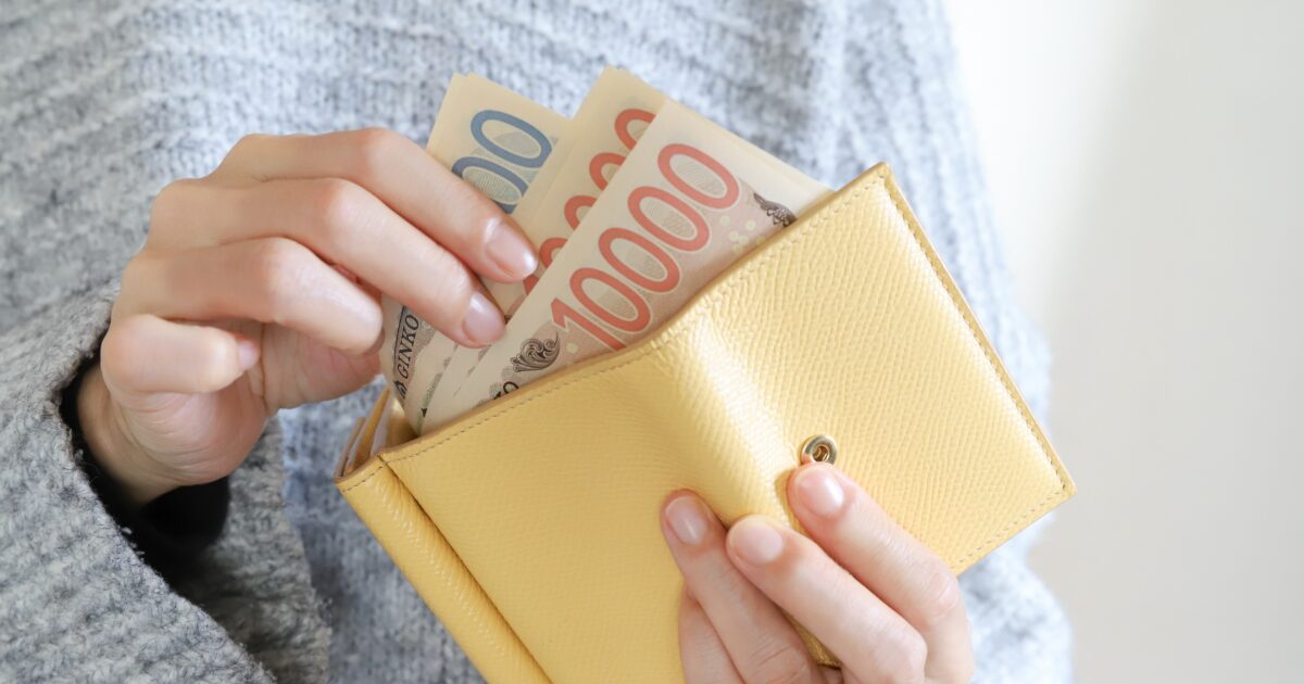 黄色の財布から日本円の紙幣を取り出す女性の手元