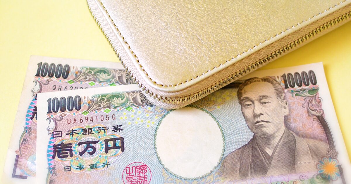 黄色のファスナー財布と一万円札で貯金や家計管理のイメージ