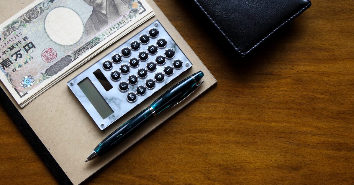 電卓とペンとノートと日本円で家計簿をつける節約イメージ