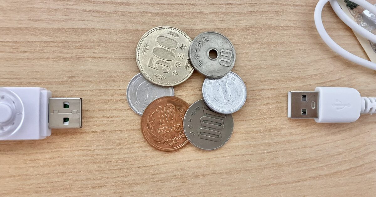 USBケーブルと日本円の硬貨を並べたキャッシュレスと現金の対比イメージ