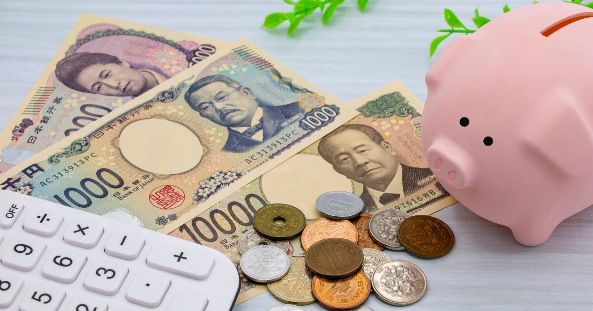日本円の紙幣と硬貨と貯金箱で表現した家計管理と節約のイメージ
