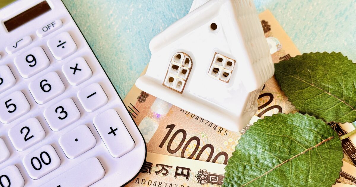 電卓と一万円札と家の模型で表す住宅費用や家計計算のイメージ