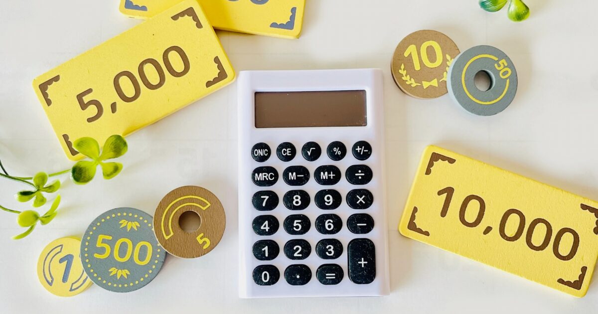 電卓とおもちゃの紙幣で表現した金額計算と予算管理のイメージ