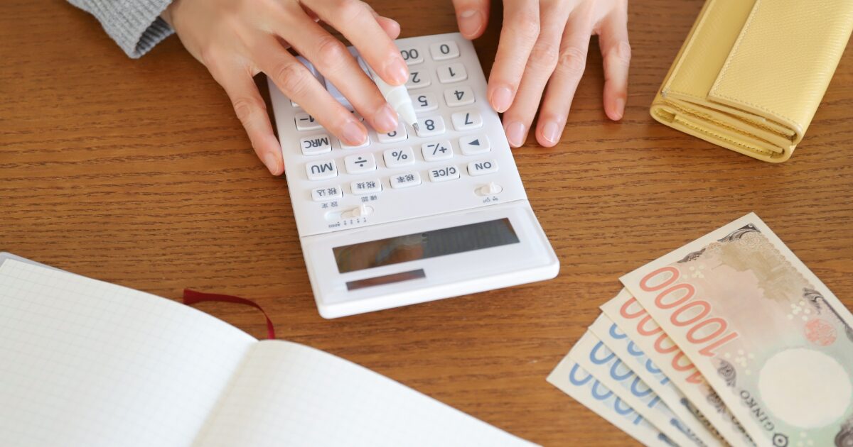 電卓で計算する手元と紙幣で表す家計簿と支出管理のイメージ